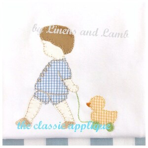 May include: A blue and white checkered applique of a boy walking with a yellow and white checkered duck. The boy is wearing a blue and white checkered shirt and brown hair. The text "by Linens and Lamb" is above the applique and "the classic applique" is below.
