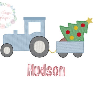 May include: A blue toy tractor pulling a wagon with a green Christmas tree inside. The wagon and tractor have white wheels. The tree has red and yellow ornaments. The text "Hudson" is written below the tractor.