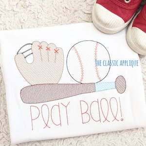 May include: A white t-shirt with an embroidered baseball, bat, glove, and the text "Play Ball!" in red thread.