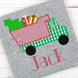 May include: A red and green Christmas truck with presents in the back. The truck has a green and white checked pattern on the sides. The name Jack is embroidered in red below the truck.