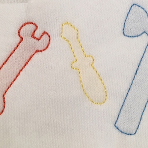 May include: Three embroidered tools on a white fabric background. A red wrench, a yellow screwdriver, and a blue hammer.