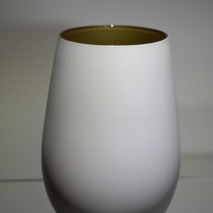 May include: A white, egg-shaped vase with a gold-colored interior rim. The vase has a smooth, matte finish and a rounded base. The design is simple and modern, suitable for home decor.