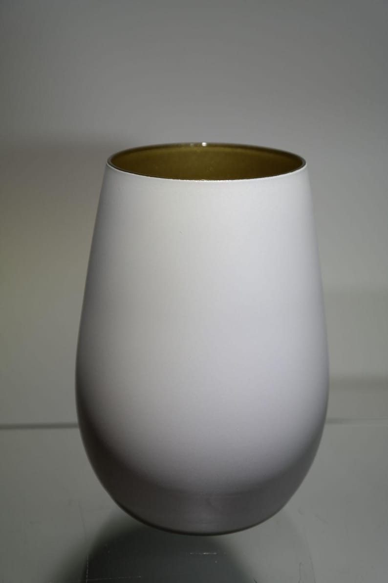 May include: A white, egg-shaped vase with a gold-colored interior rim. The vase has a smooth, matte finish and a rounded base. The design is simple and modern, suitable for home decor.