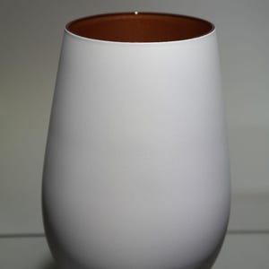 May include: A white, teardrop-shaped vase with a copper-colored interior. The vase has a smooth, matte finish and a wide opening. The design is simple and modern, suitable for home decor.