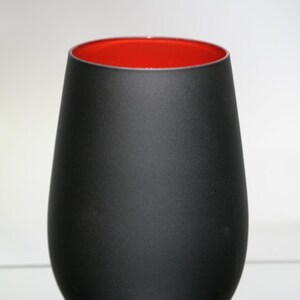 May include: A matte black glass vase with a rounded base and a wide opening. The interior of the vase is a vibrant red, creating a striking contrast. The vase has a smooth, minimalist design.