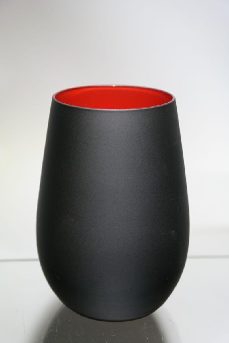 May include: A matte black glass vase with a rounded base and a wide opening. The interior of the vase is a vibrant red, creating a striking contrast. The vase has a smooth, minimalist design.
