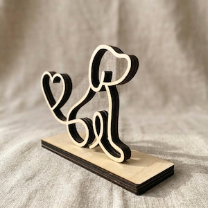 Könnte beinhalten: Eine Holzskulptur eines Hundes mit herzförmigem Schwanz. Der Hund besteht aus geschichtetem Holz mit einem dunkelbraunen Umriss und einem natürlichen Holzinnenraum. Er steht auf einem rechteckigen Holzsockel.