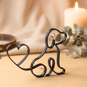 May include: A black metal dog silhouette with a heart-shaped tail. The dog is sitting, with a curved body and a heart-shaped tail. The design is simple and elegant, suitable for home decor or as a gift for dog lovers.