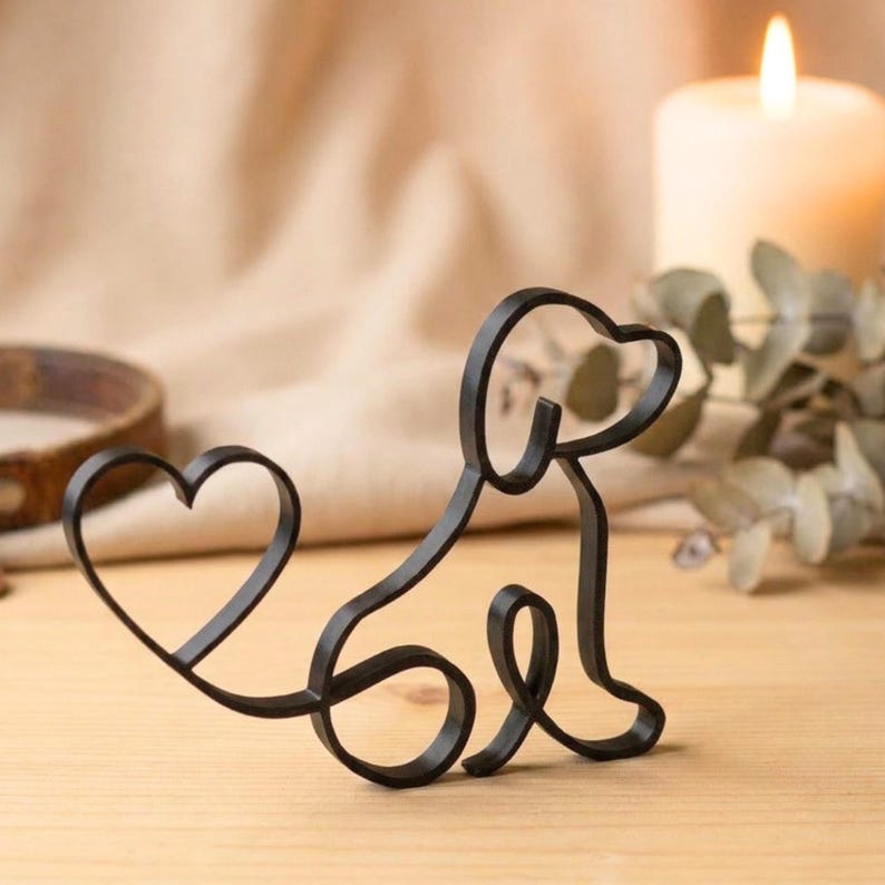 May include: A black metal dog silhouette with a heart-shaped tail. The dog is sitting, with a curved body and a heart-shaped tail. The design is simple and elegant, suitable for home decor or as a gift for dog lovers.