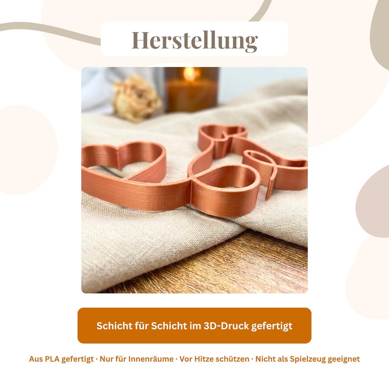 May include: A copper-colored 3D-printed cookie cutter in the shape of a heart and a bow. The text "Herstellung" is at the top. The text "Schicht f&uuml;r Schicht im 3D-Druck gefertigt" is at the bottom. The cookie cutter is on a beige cloth.