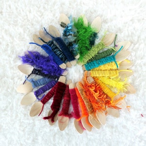 May include: A rainbow of colourful yarn wound around wooden spoons. The yarn is arranged in a circle, with each colour representing a different part of the rainbow.