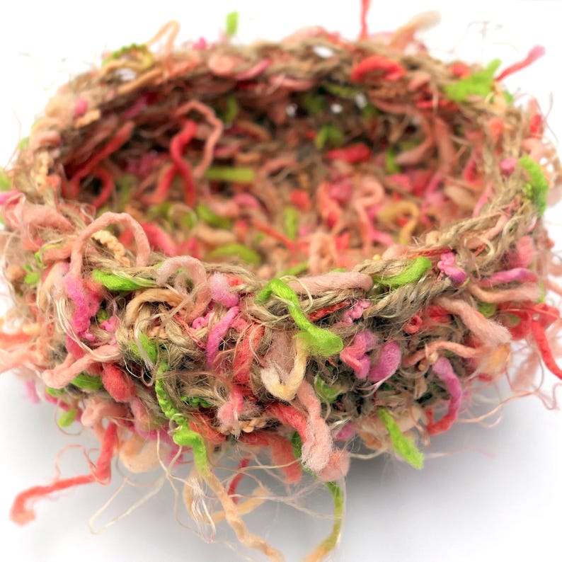 Peut inclure: Un nid tiss&eacute; en ficelle de jute naturelle et en fil color&eacute;. Le nid est de couleur brun clair avec du fil rose, vert et p&ecirc;che tiss&eacute; dans toute sa longueur. Le nid est parfait pour les accessoires de photographie de nouveau-n&eacute;s.