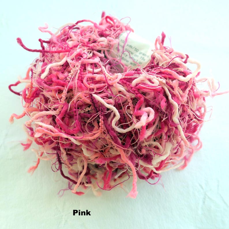 Peut inclure: Une pelote de fil rose, blanc et bordeaux avec une &eacute;tiquette indiquant "100g/50 grammes, 100% coton, 155m/170 yards, crochet 3.5mm ou 4mm, lavage en machine cycle laine".