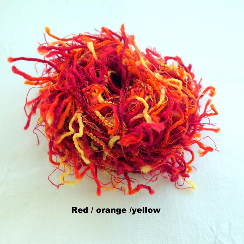 Peut inclure: Un &eacute;cheveau de fil rouge, orange et jaune avec une texture duveteuse.