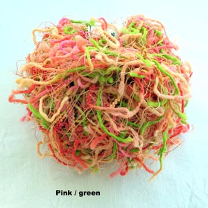 Peut inclure: Une pelote de fil rose et vert avec une texture longue, fine et vaporeuse. Le fil est parfait pour cr&eacute;er des projets uniques et d&eacute;licats.
