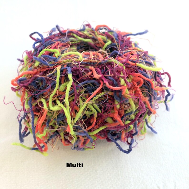Peut inclure: Un &eacute;cheveau de fil color&eacute; dans des tons de violet, vert, orange et rouge. Le fil est compos&eacute; d'un m&eacute;lange de fibres et a une texture duveteuse. Le fil est &eacute;tiquet&eacute; "Multi".