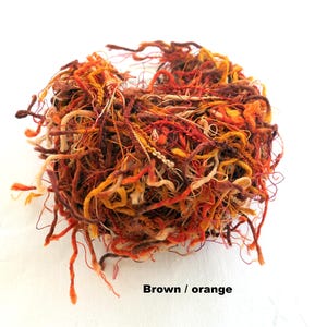 Peut inclure: Un gros plan sur un tas de fil de couleur marron, orange et cr&egrave;me. Le fil est emm&ecirc;l&eacute; et d&eacute;sordonn&eacute;, et il semble qu'il pourrait &ecirc;tre utilis&eacute; pour le tricot ou le crochet.