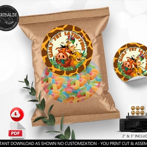 Op de afbeelding: Een bruine papieren zak gevuld met kleurrijke gummy snoepjes, met een ronde sticker met personages uit The Lion King. De sticker heeft een giraffenprint rand en de tekst "Hakuna Matata". Een PDF download icoon is zichtbaar.