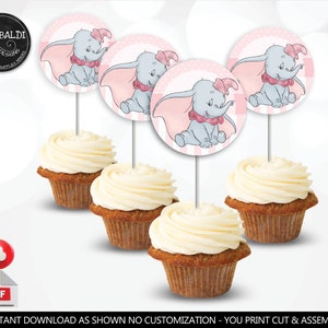 Puede incluir: Cuatro cupcakes con glaseado rosa y blanco cubiertos con toppers redondos de papel para cupcakes que muestran una imagen de dibujos animados de Dumbo el elefante. Los toppers tienen un fondo a cuadros rosa y blanco con lunares blancos.