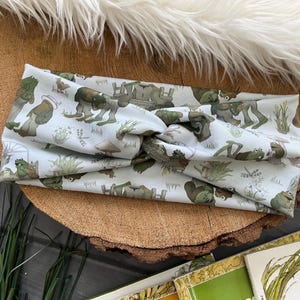 May include: A white headband with a green frog and wagon print. The headband is made of a soft, stretchy fabric and is perfect for keeping hair out of your face.