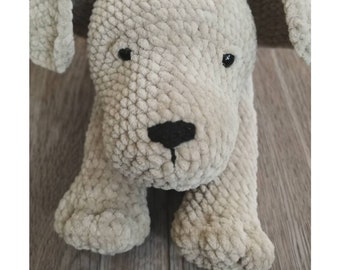 May include: A crocheted Labrador puppy toy with a red and white polka dot bow. The toy is made with a soft, fluffy yarn and has a realistic appearance. The pattern is available for purchase from Owl From The Hook.