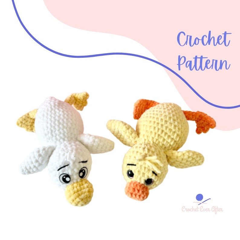 May include: Two crocheted duck plushies, one white and one yellow, lying on a white background. The ducks have black eyes and orange beaks. The text "Crochet Pattern" is written in black on a pink background.
