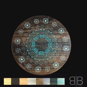 May include: A round wooden tray with a teal blue mandala design. The mandala is intricate and detailed, with a variety of geometric shapes. The tray is perfect for serving snacks, drinks, or as a decorative piece.