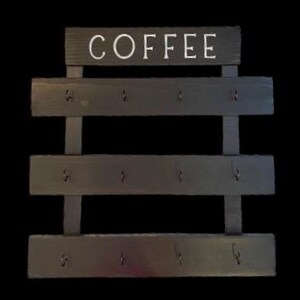 May include: A dark gray wooden wall-mounted rack featuring the word COFFEE in white capital letters at the top. The rack consists of three horizontal wooden slats, each equipped with four small metal hooks for hanging items, totaling twelve hooks.