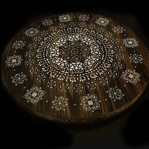 May include: A round wooden tray with a white mandala design. The tray is dark brown and has a natural wood grain.