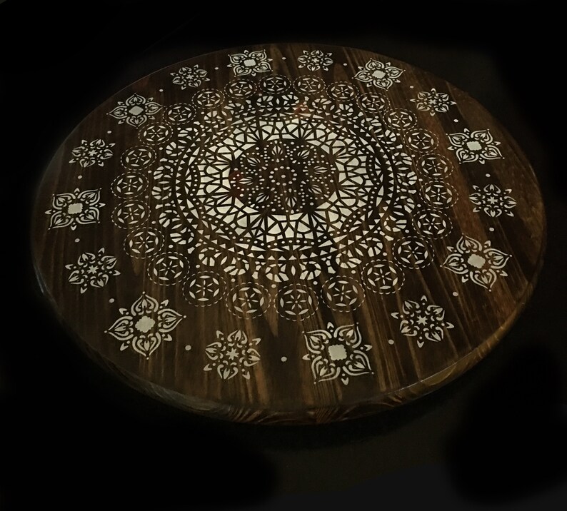May include: A round wooden tray with a white mandala design. The tray is dark brown and has a natural wood grain.