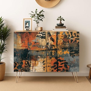 May include: A white ceramic mug with a black handle and the text "But First, Coffee" in a bold, black font. The mug is set against a blurred background, suggesting a cozy setting.