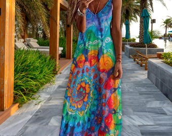 Puede incluir: Un vestido maxi colorido con cuello en V y tirantes finos. El vestido presenta un vibrante estampado tie-dye en tonos de azul, verde, naranja y amarillo. El vestido es adecuado para climas cálidos y ocasiones informales.