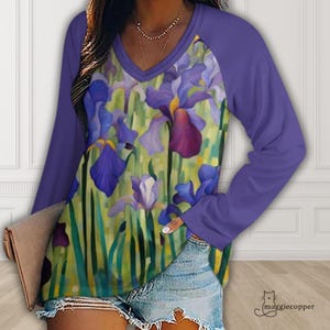May include: A long-sleeved V-neck shirt with a floral iris design. The shirt features a purple sleeve and a colorful iris print in shades of purple, blue, and yellow. The shirt is a comfortable, casual top.