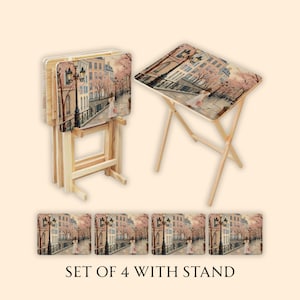 May include: Set of four decorative TV trays with a wooden stand. Each tray features a scenic painting of a European street scene with a bridge, buildings, and street lamps. The text "SET OF 4 WITH STAND" is at the bottom.