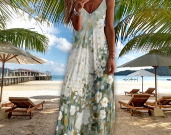 May include: A long, flowing sundress with a floral pattern in white and yellow against a light green and blue background. The dress has thin straps and a V-neckline. The image is taken on a beach with palm trees and umbrellas.