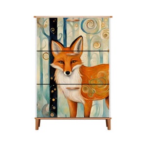 May include: A white dresser with three drawers features a colorful illustration of a fox in a forest setting. The fox is orange and white with a black nose and eyes. The forest background is blue, green, and brown with swirling patterns.