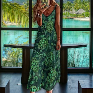 May include: A dark green, sleeveless dress with a V-neck, featuring a repeating pattern of green sea turtles. The dress is floor-length and appears to be made of a lightweight fabric. The background shows a tropical scene with palm trees and water.