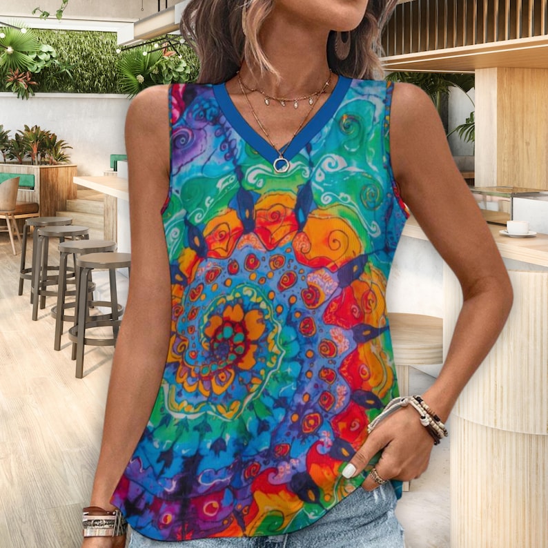 Puede incluir: Una camiseta sin mangas con cuello en V con un vibrante y colorido estampado tie-dye. El dise&ntilde;o presenta remolinos de azul, verde, naranja y rojo. La camiseta tiene un ribete azul alrededor del cuello y las sisas. Un colgante plateado cuelga del escote.