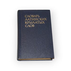 Könnte beinhalten: Ein blaues Hardcover-Buch mit goldener Beschriftung auf dem Rücken, die "Словарь Латинских Крылатых Слов" lautet.