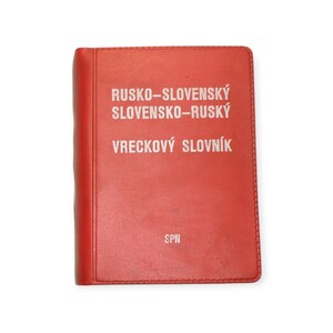 Op de afbeelding: Een rood zakwoordenboek met witte tekst. De omslag luidt "RUSKO-SLOVENSKÝ SLOVENSKO-RUSKÝ VRECKOVÝ SLOVNÍK" en "SPN" onderaan. Het boek is gesloten en heeft een gestikte rand.