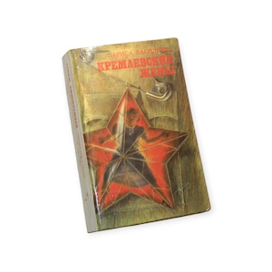 Peut inclure: Un livre à couverture rigide avec une couverture dorée ornée d'une étoile rouge et du titre en texte rouge. Le livre est maintenu par une épingle de sûreté. Le titre du livre est en russe.