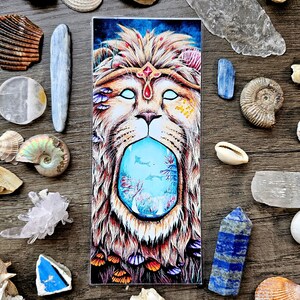 May include: A colorful illustration of a lion's head with a blue, underwater scene inside its mouth. The lion has a crown of flowers and a jeweled forehead. The underwater scene features coral, fish, and seaweed.