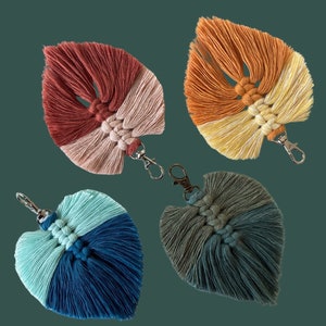 May include: Four mini macrame feather keychains in different color combinations: red and pink, orange and yellow, blue and green, and green and gray. Each keychain has a silver metal ring.