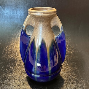 May include: A white ceramic mug with a black handle and the text "But First, Coffee" in a bold, black font. The mug is set against a neutral background, highlighting its simple design.