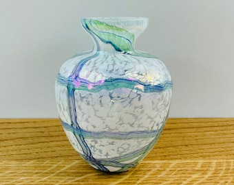 May include: A small white glass vase with a textured surface and blue and green iridescent stripes.