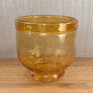 May include: A clear amber glass vase with a textured bubbled surface. The vase has a wide mouth and a rounded base.