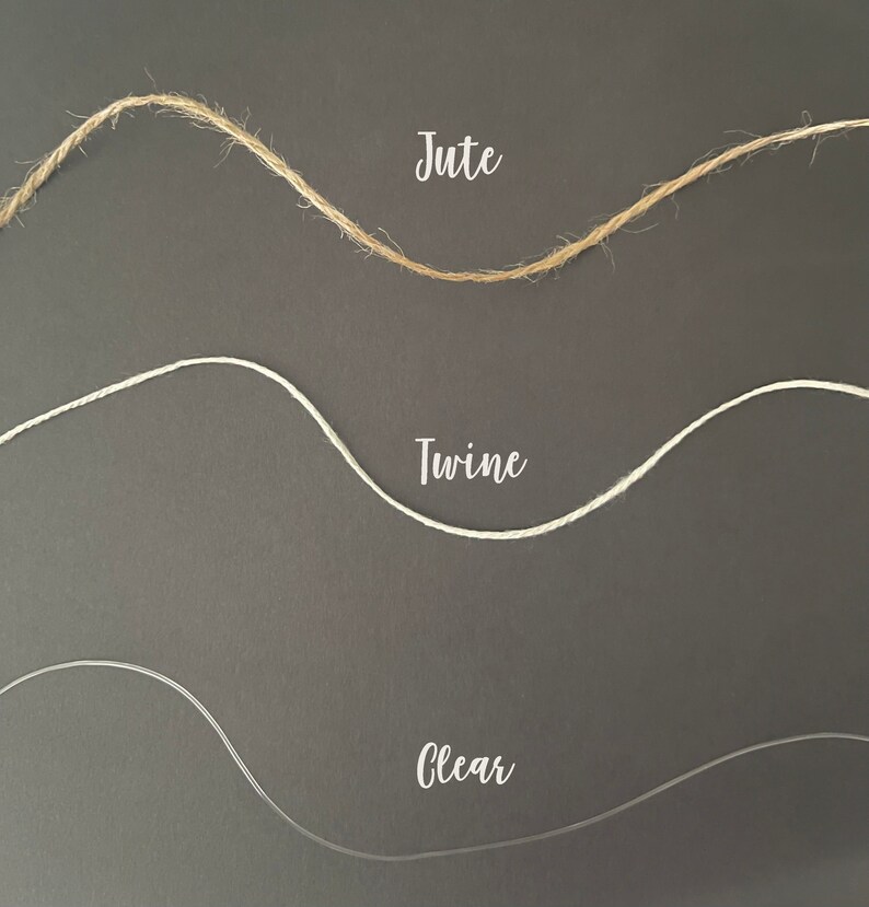 May include: Three different types of string: jute, twine, and clear. The strings are arranged in a wavy pattern on a dark grey background.