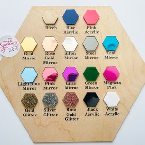 May include: A wooden hexagon chart displaying a range of colour and material choices for a personalised sign. The options include birch, blue acrylic, pink acrylic, gold mirror, rose gold mirror, silver mirror, steel mirror, teal mirror, light blue mirror, pink mirror, lilac mirror, green mirror, magenta pink, gold glitter, silver glitter, rose gold glitter, black acrylic, and white acrylic.