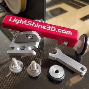 May include: A red 3D printed lever with the text "LightShine3D.com" on it. The lever is attached to a silver metal base with a spring and a screw. There are two silver metal screws, a silver metal wrench, and a silver metal washer with a black rubber ring.