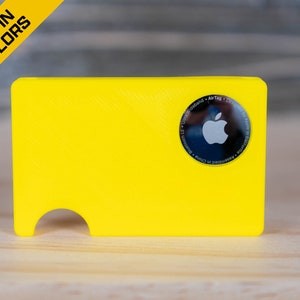 May include: A bright yellow plastic card holder with a cut-out for an Apple AirTag. The AirTag is visible in the holder, showing the Apple logo.